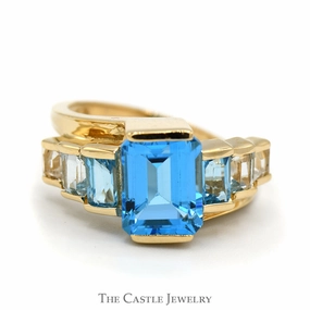 Timeless Present Emerald Cut Blue Topaz Ring with Graduated Design in 14k Yellow Gold Bypass Setting