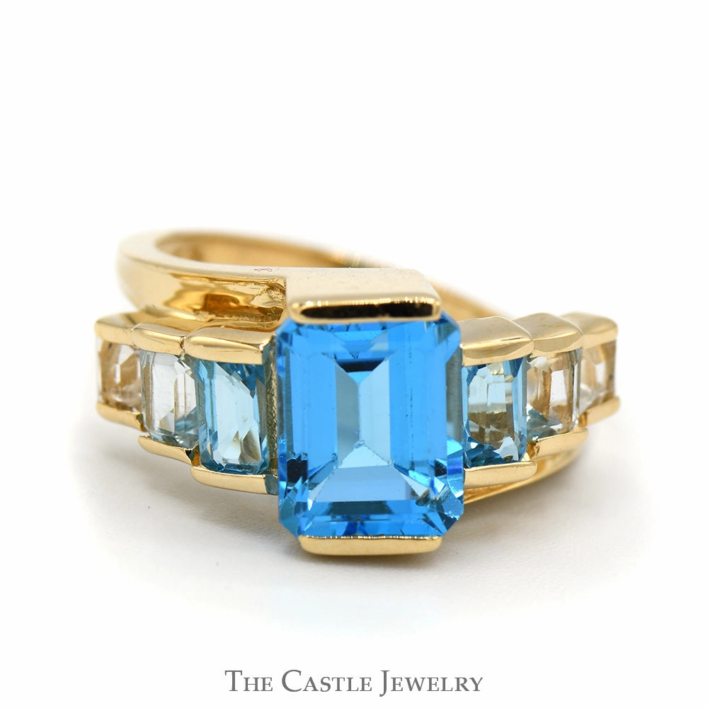 Timeless Present Emerald Cut Blue Topaz Ring with Graduated Design in 14k Yellow Gold Bypass Setting